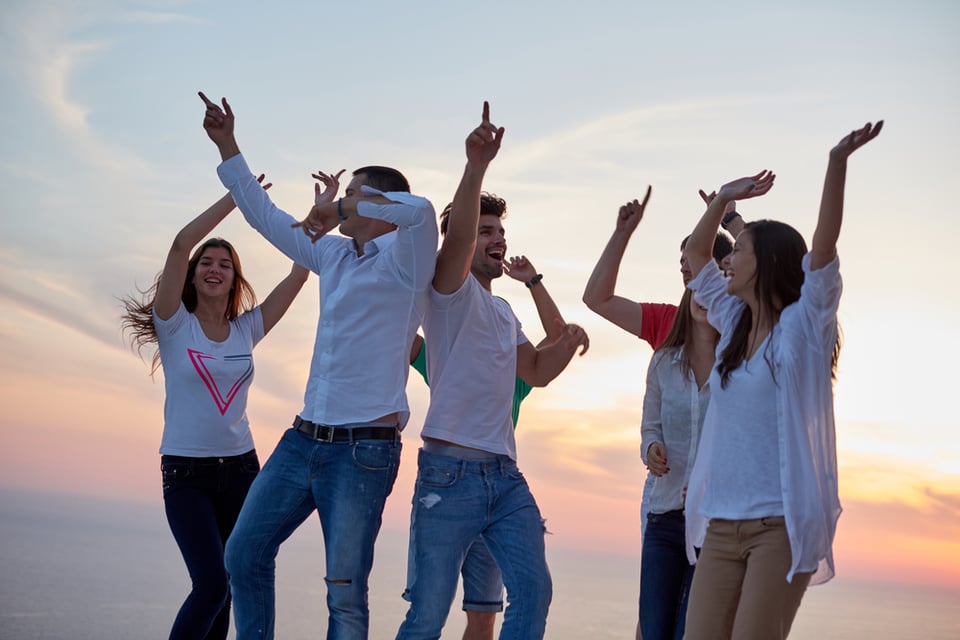 group of happy young people dancing and have fun on party in modern home bacony with sunset and ocean in background-1